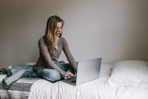 woman using her laptop while sitting on her bed